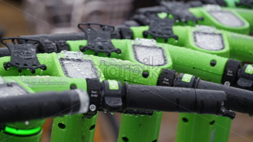 Video – Milan, Italy – March 23, 2025: Close up of green electric scooters parked on the street in the rain in daylight - Starpik Stock