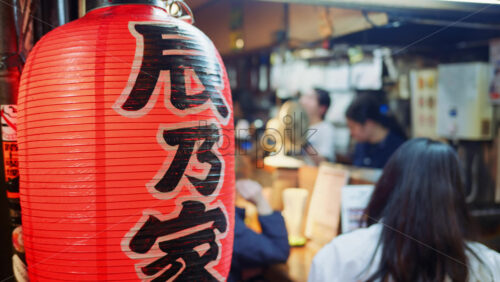 Video - Shinjuku, Japan - April 12, 2025: People sitting at a traditional Japanese restaurant on the Omoide Yokocho Memory Lane in the evening. Translation: "Izakaya"