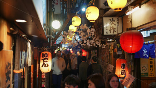 Video - Shinjuku, Japan - April 12, 2025: People walking on the Omoide Yokocho Memory Lane in the evening. Translation: "Oden, Kushiyaki"