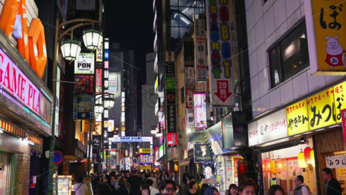 Video - Tokyo, Japan - April 12, 2025: View of the vibrant life of Shinjuku City with people moving on the streets with lighted buildings in the evening. Translation: "Company names"