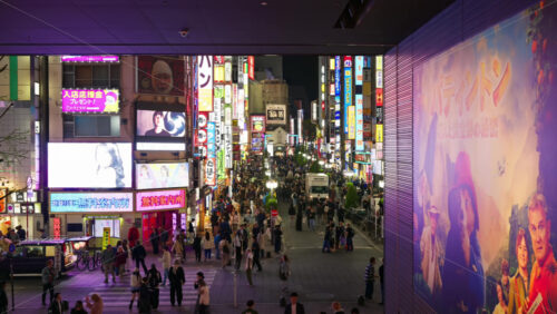 Video - Tokyo, Japan - April 12, 2025: View of the vibrant life of Shinjuku City with people moving on the streets with lighted buildings in the evening. Translation: "Company names"