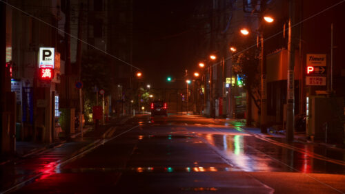 Video - Tokyo, Japan - April 13, 2025: People and cars moving on the streets of the city with orange lights on a rainy evening. Translation: "Full praking"