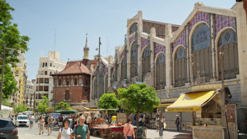 Video – Valencia, Spain – May 28, 2025: Wide, daylight establishing shot of the Mercado Central with ornate iron and glass arches with colourful ceramic panels, seen from the surrounding plaza - Starpik Stock