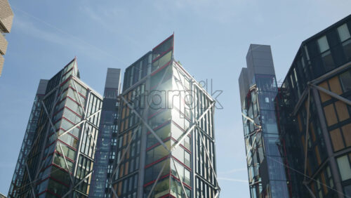 View of a modern glass office buildings in London, England with sunlight reflecting off windows - Starpik Stock