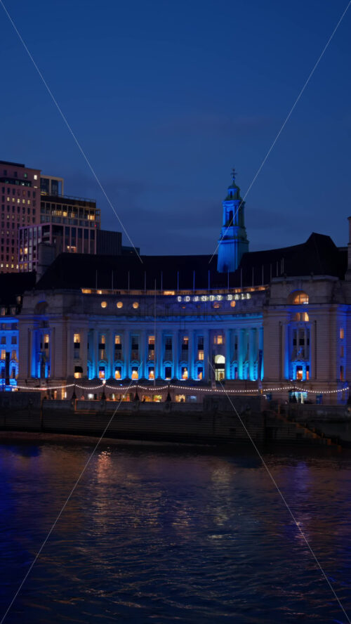 View of the County Hall lit in green, blue, and pink in the evening. Vertical, London - Starpik Stock