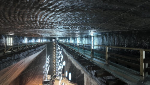 View of the Turda salt mine with wooden railings, walkways, and artificial lighting in Turda, Romania - Starpik Stock