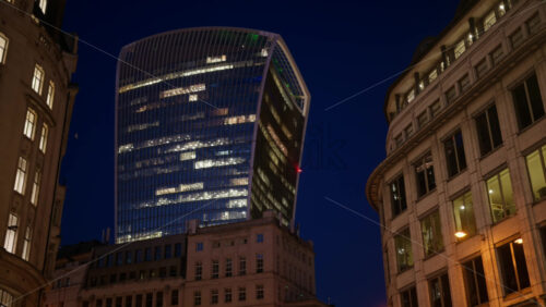 View of the Walkie-Talkie skyscraper standing tall above surrounding architecture in the evening blue hour, London, England - Starpik Stock