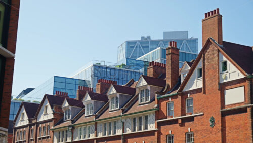 View of traditional red-brick townhouses with modern glass office buildings in the background in London, England - Starpik Stock