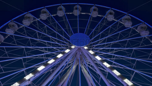 View of white, illuminated ferris wheel rotating in Antibes, France in the evening - Starpik Stock