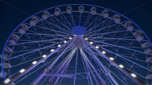 View of white, illuminated ferris wheel rotating in Antibes, France in the evening - Starpik Stock