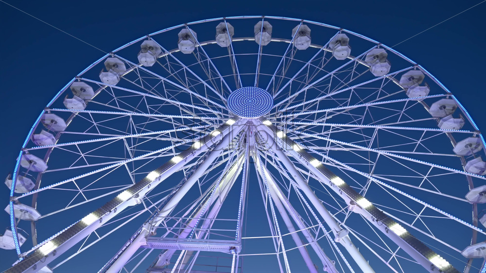View of white, illuminated ferris wheel rotating with the sky on the background in Antibes, France - Starpik Stock