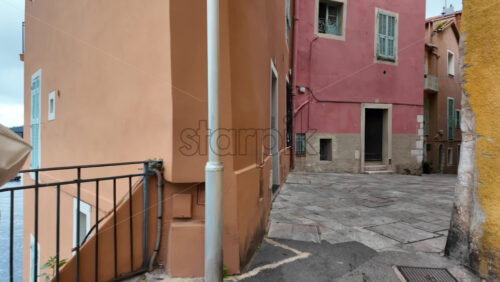 Villefranche-sur-Mer, France – July 18, 2025: A walk on a narrow street between pastel buildings in daylight - Starpik Stock