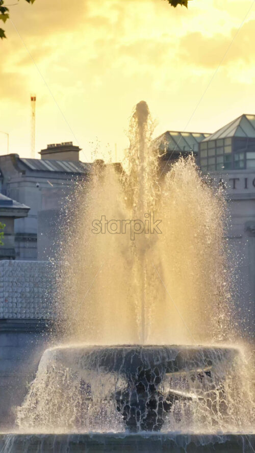 Water fountain in the Trafalgar Square in London, England on a sunny evening. Vertical - Starpik Stock