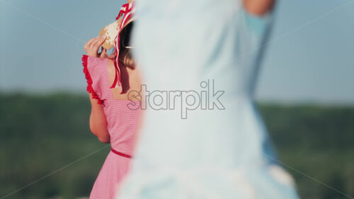 Woman in a red gingham dress and wide hat with a ribbon walking on a terrace - Starpik Stock