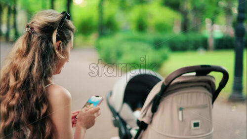 Woman looking at a picture on her phone while sitting on a park bench - Starpik Stock