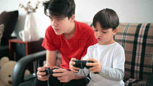 Video - Two brothers are playing console games using controllers. Different ages