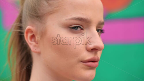 Video - Young focused blonde woman at outdoors training, multicolored background. Slow motion