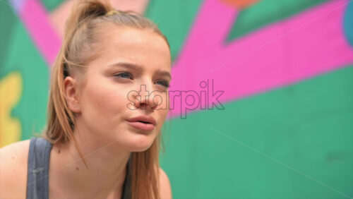 Video - Young focused blonde woman at outdoors training starting to run, multicolored background. Slow motion