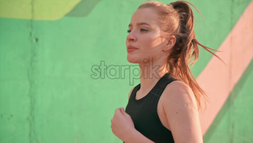 Video - Young blonde woman in sportswear running on the road at outdoors training. Slow motion