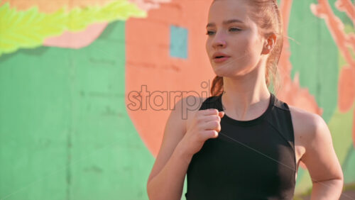 Video - Young blonde woman in sportswear running on the road at outdoors training. Slow motion