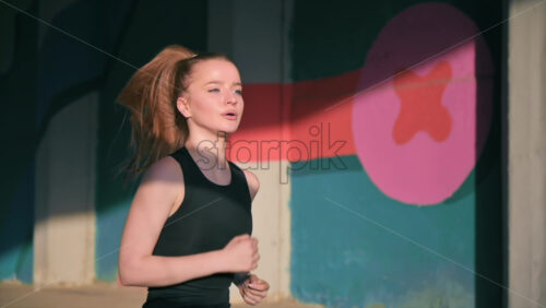 Video - Young blonde woman in sportswear running on the road at outdoors training. Slow motion, sunset