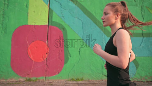Video - Young blonde woman in sportswear running on the road at outdoors training. Slow motion, sunset