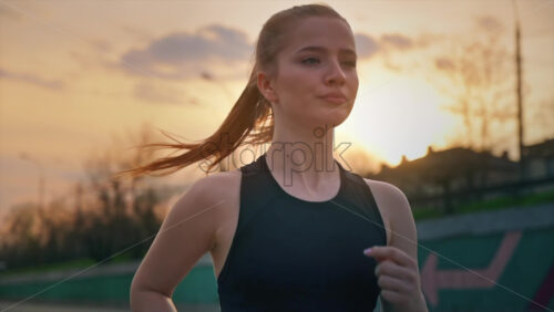 Video - Young blonde woman in sportswear running on the road at outdoors training. Slow motion, sunset