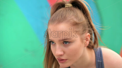 Video - Young focused blonde woman at outdoors training starting to run, multicolored background. Slow motion
