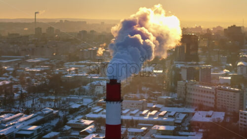 Video - Aerial drone view of a working thermal power station in Chisinau city covered in snow at sunset. Steam and smoke coming from pipes. Moldova