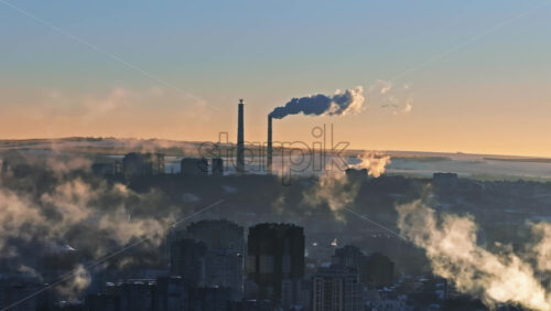 Video - Aerial drone view of a working thermal power station in Chisinau during winter at sunset. Steam and smoke coming from pipes. Moldova