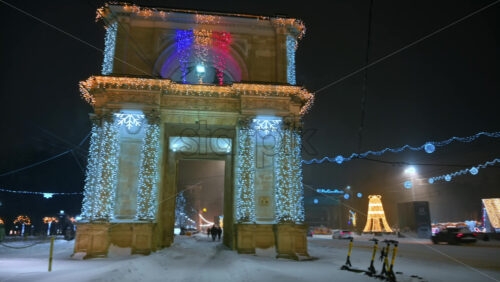 Video - Chisinau, Moldova - January 09, 2024: The Triumphal Arch on the Great National Assembly Square during snowfall in the evening. Christmas decorations