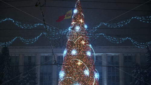 Video - Chisinau, Moldova - January 09, 2024: Artificial Christmas tree with decorations on the Great National Assembly Square during snowfall. Winter evening
