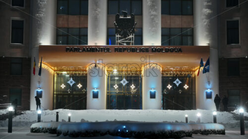 Video - Chisinau, Moldova - January 09, 2024: Parliament building with national emblem, illumination and Christmas decorations. Ground covered in snow. Winter evening