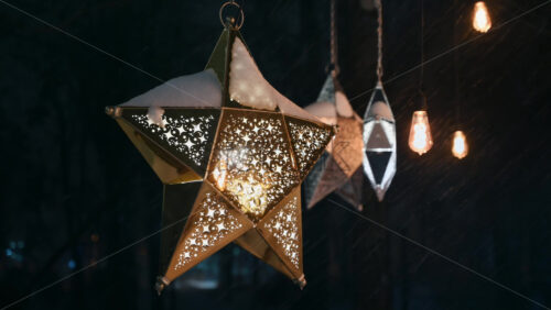 Video - Close up view of the star-shaped lanterns in the park during snowfall. Christmas decorations. Winter evening