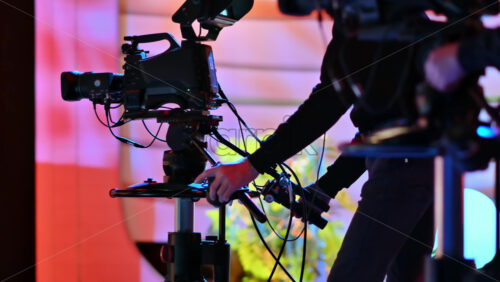 Video - Cameraman filming a television show on a professional camera. Video production backstage in a dark studio