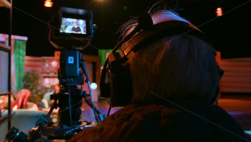 Video - Cameraman filming a television talk show on a professional camera. Video production backstage in a dark studio