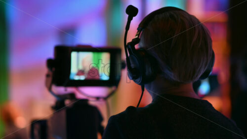 Video - Cameraman filming a television talk show on a professional camera. Video production backstage in a dark studio