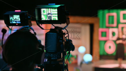 Video - Cameraman filming a television talk show on a professional camera. Video production backstage in a dark studio