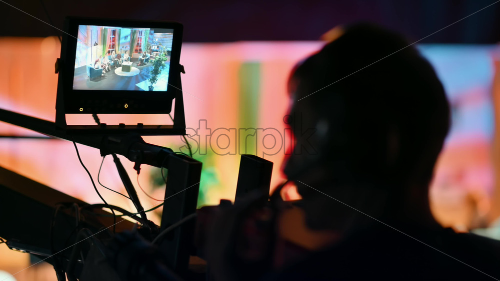 Video - Cameraman filming a television talk show on a professional camera mounted on the crane. Video production backstage in a dark studio