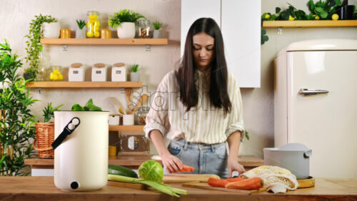 Video - Young woman recycling vegetables peels in a compost bin. Housewife cooking food and composting organic waste in a bokashi container at home. Ecological and sustainability concept