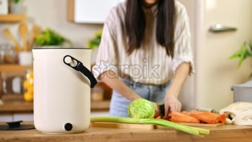 Video - Young woman recycling vegetables peels in a compost bin. Housewife cooking food and composting organic waste in a bokashi container at home. Ecological and sustainability concept