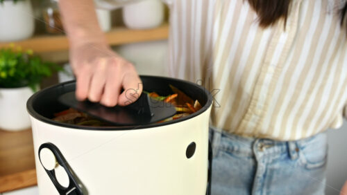 Video - Young woman press vegetables peels in a compost bin. Housewife cooking food and composting organic waste in a bokashi container at home. Ecological and sustainability concept