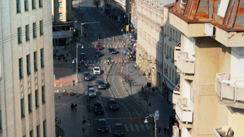 Video - Bucharest, Romania - March 03, 2024: Aerial drone view of a downtown road with moving traffic and walking people. Sunny day