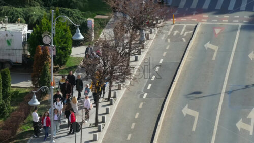 Video - Bucharest, Romania - March 03, 2024: Aerial drone view of a downtown road with moving traffic and walking people in sunlight