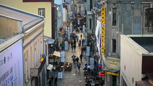 Video - Bucharest, Romania - March 03, 2024: Walking people among old historical buildings and commercial shops in the old town