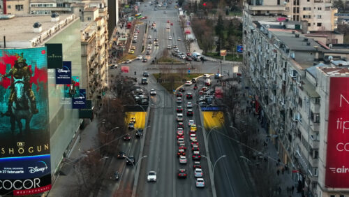 Video - Bucharest, Romania - March 03, 2024: Aerial drone view of a downtown intersection with moving traffic and walking people
