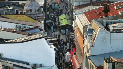 Video - Bucharest, Romania - March 03, 2024: Walking people among old historical buildings and commercial shops in the old town