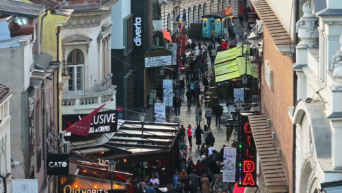 Video - Bucharest, Romania - March 03, 2024: Walking people among old historical buildings and commercial shops in the old town