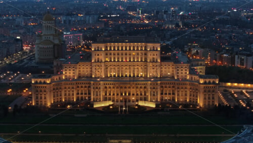 Video - Aerial drone view of illuminated Palace of the Parliament in Bucharest downtown in the evening. Multiple districts around. Romania