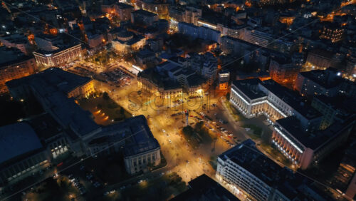 Video - Aerial drone view of Carol I University Foundation in the night. Main building with Carol I statue in front of it, roads and buildings. Illuminated Bucharest city, Romania